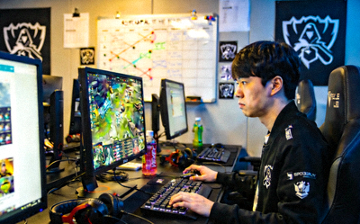 明星中单选手Faker在训练室中专注地看着电脑屏幕，侧脸严肃